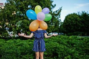 hermosa chica morena en la calle de la ciudad con globos en las manos. foto