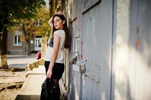 Stylish brunette girl wear on leather jacket and shorts posing at street. photo