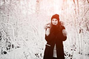 Beautiful brunette girl in winter warm clothing. Model on winter jacket and black hat. photo