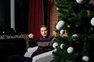 retrato de estudio del hombre contra el árbol de navidad con adornos. foto