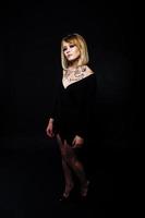 Studio portrait of blonde girl with originally make up on neck, wear on black dress at dark background. photo