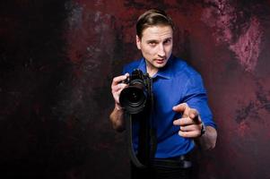 retrato de estudio de un elegante fotógrafo profesional con cámara, vestido con camisa azul y corbata. foto