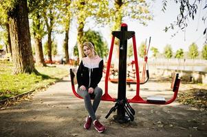 la joven tiene el entrenamiento y hace ejercicio al aire libre en simuladores callejeros. deporte, fitness, concepto de entrenamiento callejero. foto