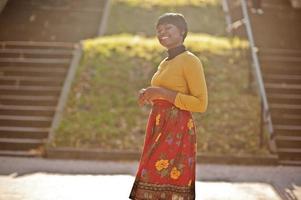 African american girl at yellow and red dress at golden autumn fall park. photo