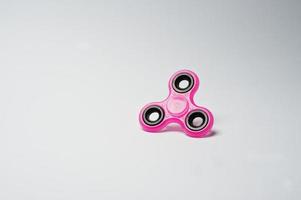 Close-up photo of a pink fidget spinner on a white background.