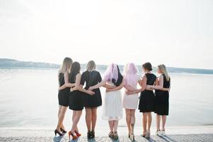 Back of group of 7 girls wear on black and 2 brides at hen party. photo