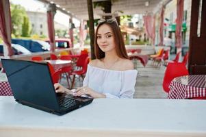 retrato de una fuerte y exitosa mujer de negocios independiente que usa ropa informal elegante y gafas que trabajan en una laptop en un café. foto