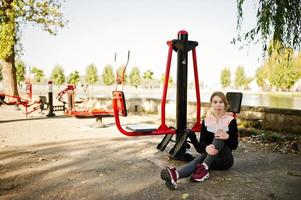 Young girl has the training and doing exercise outdoors on street simulators. Sport, fitness, street workout concept. photo