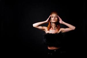 Fashion model red haired girl with originally make up like leopard predator isolated on black. Studio portrait. photo