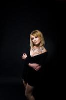 Studio portrait of blonde girl with originally make up on neck, wear on black dress at dark background. photo