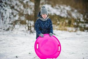 Cute little girl with saucer sleds outdoors on winter day. photo