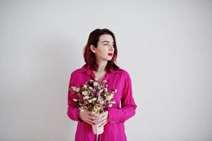 Red haired girl with dried bouquet at rose shirt against white wall at empty room. photo