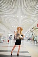 retrato de una mujer con blusa de leopardo, falda negra posando en un centro comercial con sombrero y una taza de café. foto