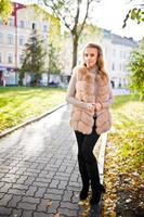 Blonde girl at fur coat at autumn street on pavement. photo