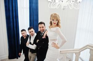 Three stylish bearded man well dressed with one blonde girl in white dress posed. Musician band or singers. photo