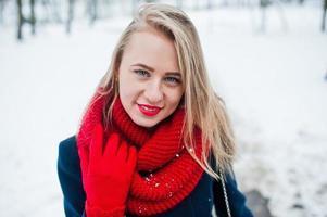 Portrai of blonde girl in red scarf and coat on winter day. photo