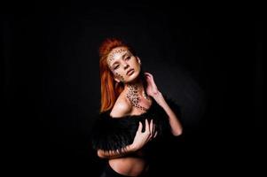 Fashion model red haired girl with originally make up like leopard predator isolated on black. Studio portrait. photo