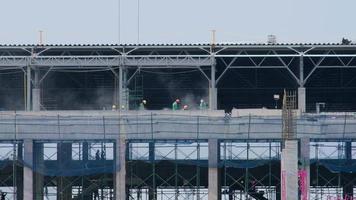 werknemers werken op constructies van gewapend beton op de bouwplaats. een grote bouwplaats met arbeiders die in de schemering werken. video