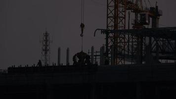 Time lapse of a large construction site with many busy cranes and workers working at dusk. Concepts of technology and construction industry