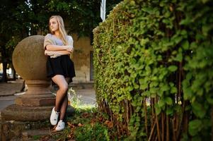 Young blonde girl in black skirt with scarf posed at street of city. photo