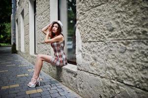 Amazing long legs with hig heels girl wear on hat sitting on the window sill on streets of city. photo