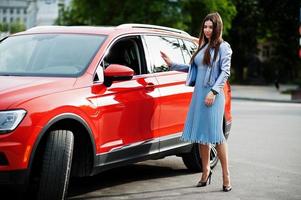 Outdoor photo of gorgeous woman posing near orange suv car.