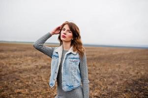 Portrait of brunette curly girl in jeans jacket at field. photo