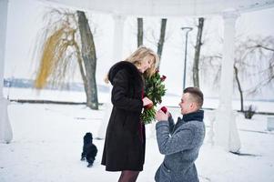 Married proposal with 101 rose at winter day. Loving couple. photo