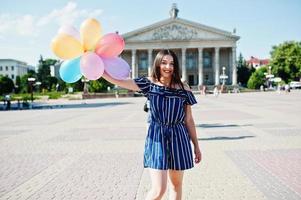 hermosa chica morena en la calle de la ciudad con globos en las manos. foto