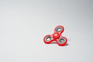 Close-up photo of a red fidget spinner on a white background.