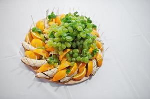 Plate full of bananas, oranges, grapes and mint leaves. photo