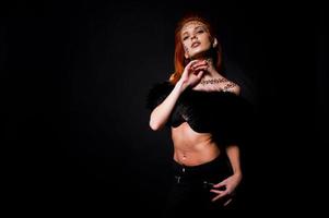 Fashion model red haired girl with originally make up like leopard predator isolated on black. Studio portrait. photo