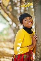 African american girl at yellow and red dress at golden autumn fall park. photo