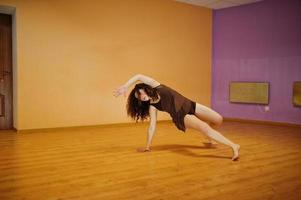 Curly brunette plus size model doing acrobatic at dance room. photo