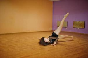 Curly brunette plus size model doing acrobatic at dance room. photo