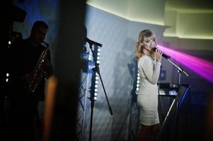 Musicial music live band performing on a stage with different lights. Beautiful blonde vocal singer girl. photo