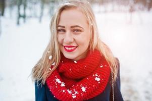 Portrai of blonde girl in red scarf and coat on winter day. photo