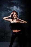 Fashion model red haired girl with originally make up like leopard predator against steel wall. Studio portrait. photo