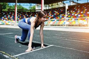 Portrait of a strong fit girl in sportswear running in the stadium. photo