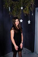 linda chica vestida de negro contra la decoración navideña. foto