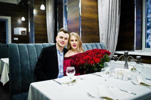 Loving couple in love at restaurant with large bouquet of 101 roses. photo