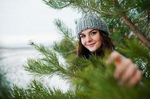 Portrait of gentle girl in gray coat and hat against new year tree outdoor. photo