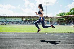 Portrait of a strong fit girl in sportswear running in the stadium. photo