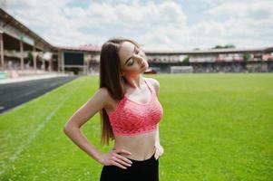 Fitness sporty girl in sportswear at a football stadium outdoor sports. Happy sexy woman workout on the background of green grass. photo