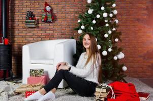 Cute girl wear on warm sweaters, black pants against new year tree with christmas decoration at studio. photo