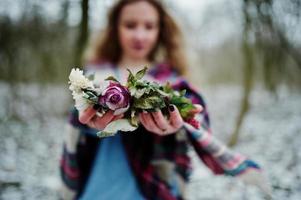 Ggirl holding wreath on hands at snowy forest in winter day. photo