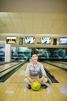 Girl with bowling ball on alley played at bowling club. photo