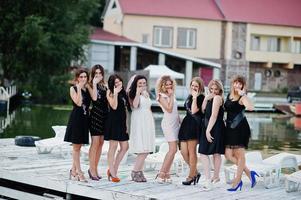 grupo de 8 chicas vestidas de negro y 2 novias en una despedida de soltera en el muelle al lado de la playa. foto