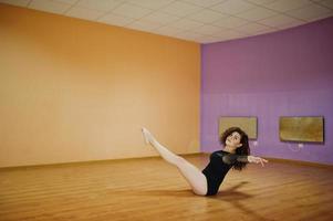 Curly brunette plus size model doing acrobatic at dance room. photo