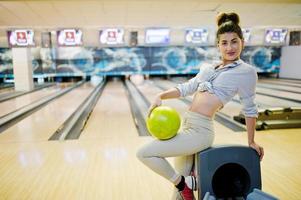 Girl with bowling ball on alley played at bowling club. photo